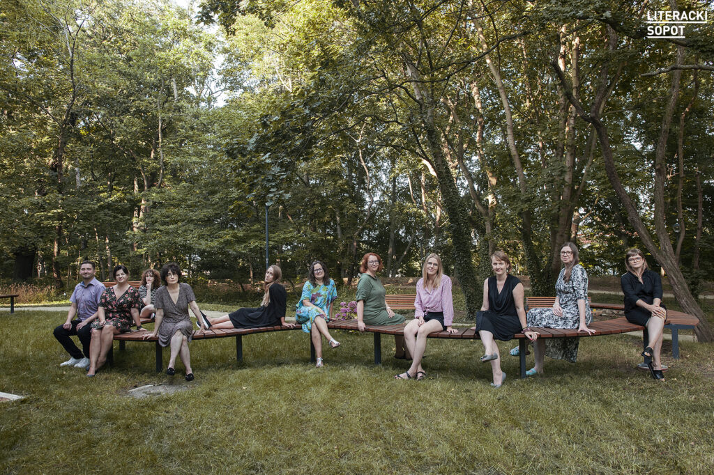 zdjęcie przedstawia grupe osób siedzących w parku na ławce